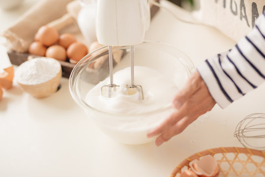 Mixing white egg cream in bowl with motor mixer, baking cake