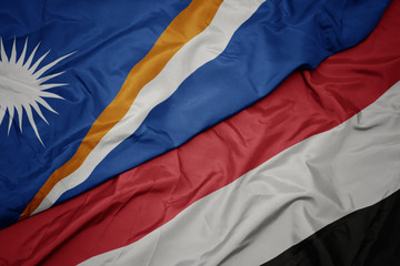 waving colorful flag of yemen and national flag of Marshall Islands .