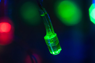 Green LED light bulb Christmas garland close-up macro bokeh. Background with place for text.