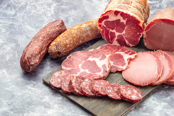 Assortment of delicious deli meats on wooden board