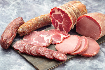 Assortment of delicious deli meats on wooden board