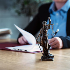 Lawyer office. Statue of Justice with scales and lawyer working on papers, Advice and justice...