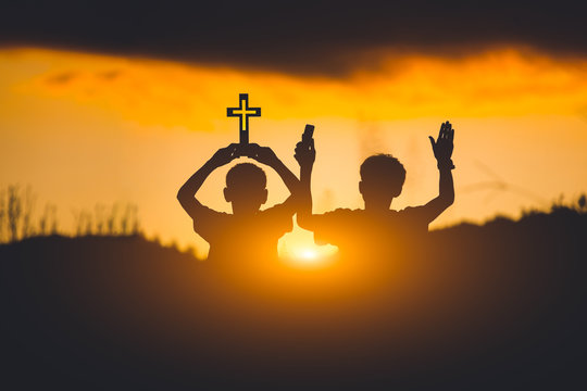 Silhouette of two young christian worshiping God ,christian concept.