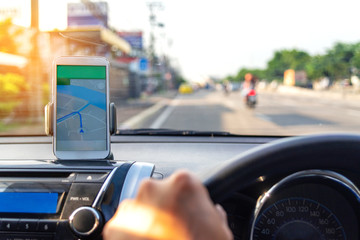 The map on the phone in the background of the dashboard and street . White mobile phone with map...
