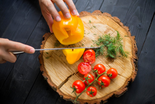 Chef cook cuts yellow bell pepper on a wooden board, closeup. - Powered by Adobe