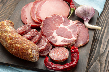Antipasto platter cold meat with slices ham, beef jerky, salamon wooden board over rustic background