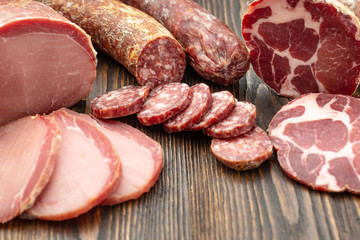 Antipasto platter cold meat with slices ham, beef jerky, salamon wooden board over rustic background