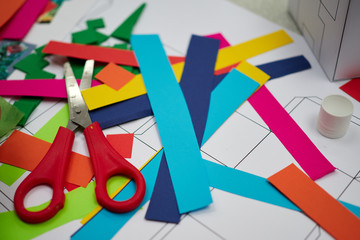 A childrens craft session in front of a teacher cutting up colourful paper with scissors