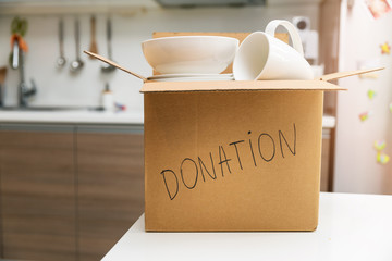 donate household items - box with tableware for donation on kitchen table