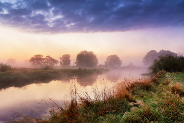 Fototapeta na wymiar Dramatic colorful scenery. Dawn on riverbank. Misty morning on river.