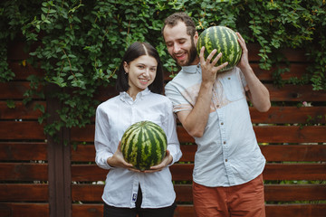 Fototapeta premium Portrait of a happy couple with a watermelon in their hands. Wooden background.
