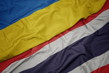 waving colorful flag of thailand and national flag of ukraine.