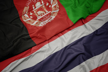 waving colorful flag of thailand and national flag of afghanistan.