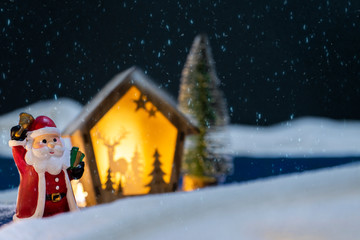 Santa Claus  holding a gift box  and ringing a bell with shadow of rendear and christmas tree on a dark night  background with snow,.