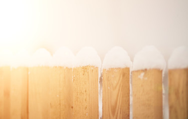 fence in the snow. on a wooden fence snowflakes. Sun ray. snow on the fence