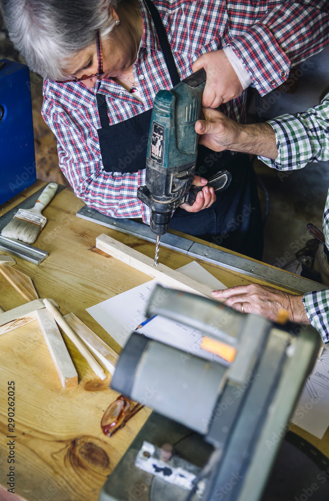 Wall mural Senior woman working in a carpentry workshop with her husband