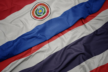 waving colorful flag of thailand and national flag of paraguay.