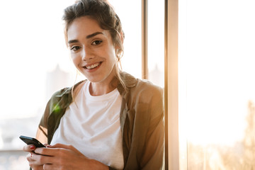 Image of stylish woman holding smartphone at terrace outdoors