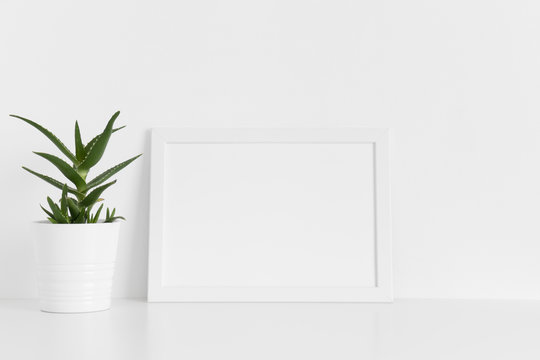 White frame mockup with a aloe vera in a pot on a white table.Landscape orientation.