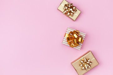 Golden gift or present boxes on pink background top view. Festive composition for birthday, christmas or wedding. Flat lay.