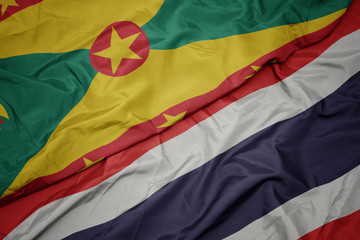waving colorful flag of thailand and national flag of grenada.