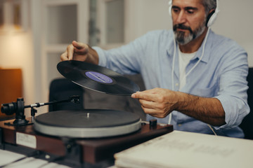 close up of middle aged man sitting sofa and listening music on record player in his home