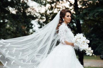 Woman in fashionable dress waving veil wind. Stylish and beautiful. Bridal bouquet of orchids. Female fashion. Beautiful woman with professional make up and hairstyle. Beautiful woman