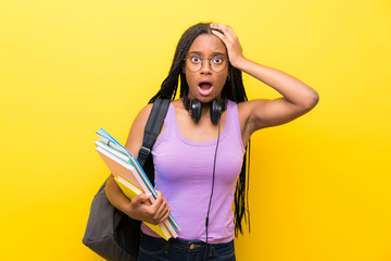 African American teenager student girl with long braided hair over isolated yellow wall with surprise facial expression