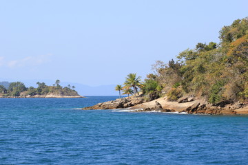 Fototapeta na wymiar Island with green vegetation surrounded by blue ocean and clean sky. Region of Paraty, Brazil