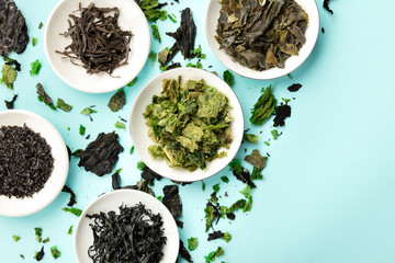 Various dry seaweed, sea vegetables, shot from above on a blue background with copy space