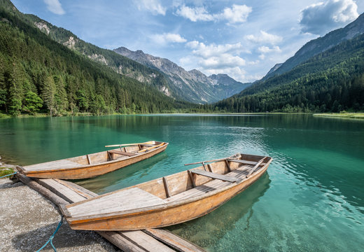 Scenic mountain landscape with turquoise lake and wooden boat at sunny summer day in Austria Alps