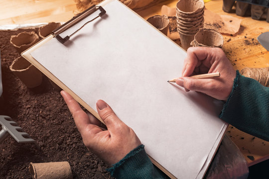 Gardener writing notes on clipboard note paper, mock up