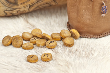 Wooden runes with symbols and alphabet close up. Pagan mascots are scattered on the table.