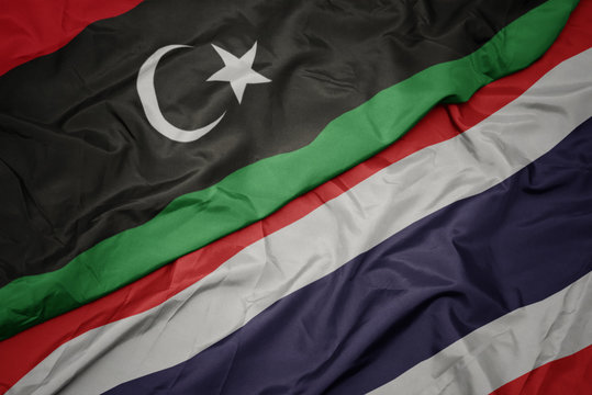 waving colorful flag of thailand and national flag of libya.