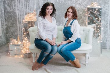 Two very pretty girls celebrates Christmas, new year. Girls in the New Year's interior of the room...