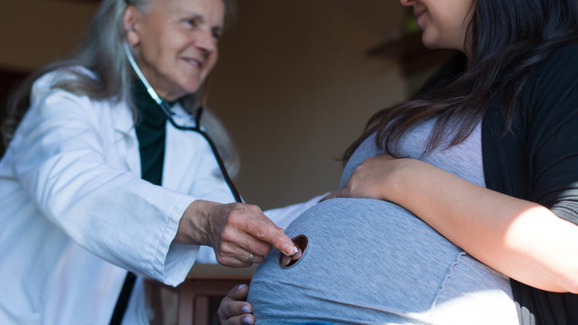 Female doctor examined pregnant woman with a stethoscope