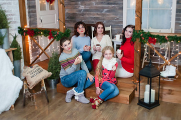Several very pretty women and a teenager girl celebrate Christmas, the new year. Girls in the New Year's interior with cups in their hands