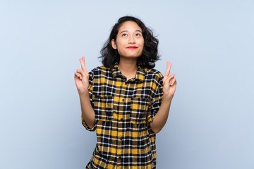 Asian young woman over isolated blue background with fingers crossing and wishing the best