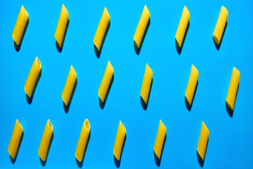 Yellow pasta on a blue background in hard light. Flat lay from macaroni