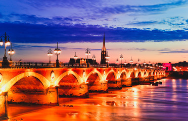 Pont de Pierre stone bridge at sunset with the st michel church in the background.