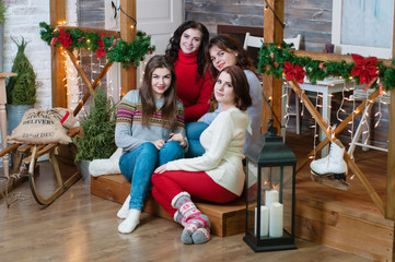 The company of beautiful women in the New Year's interior at home. Cute young women celebrate New Year or Christmas