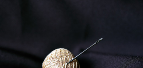 steel tailor's needle in a coil with threads in the folds of the fabric