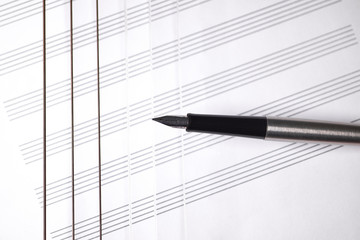 guitar strings and pen with a white sheet of paper for musical notes.