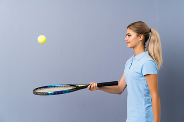 Teenager tennis player girl over grey wall