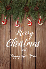 Christmas composition of tree branches, candies and decorations on wooden background. Top view. Copy space.