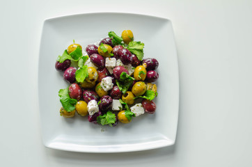 Fresh Greek salad based on green and black olives with pieces of white feta cheese and parsley
