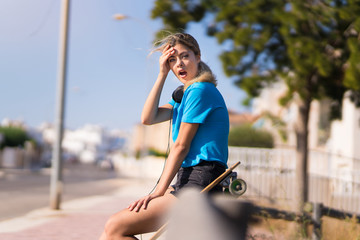 Teenager girl with skate at outdoors with surprise expression