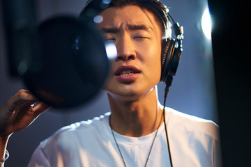 young asian singer singing in recording studio - obrazy, fototapety, plakaty