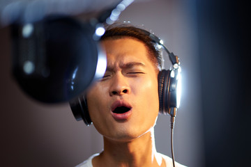 young asian singer singing in recording studio