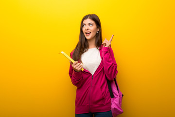 Teenager student girl on vibrant yellow background thinking an idea